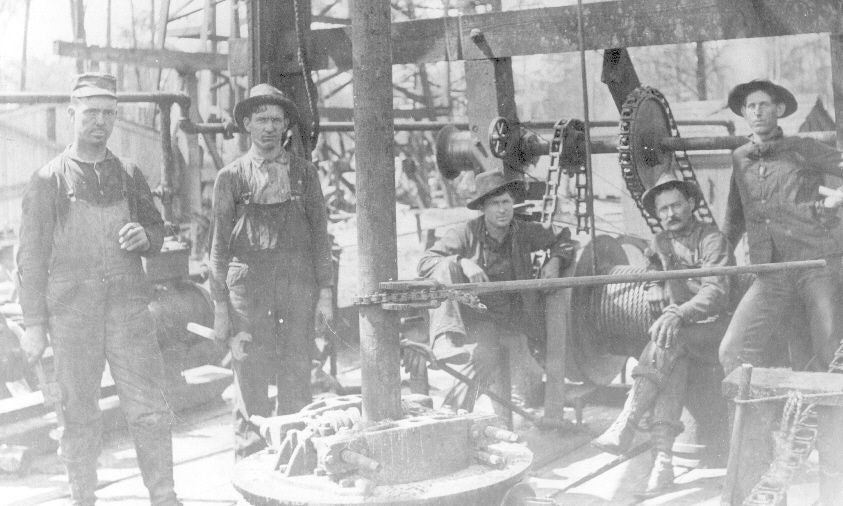 A crew of early-1900s oilfield wildcatters at a cable-tool drilling rig